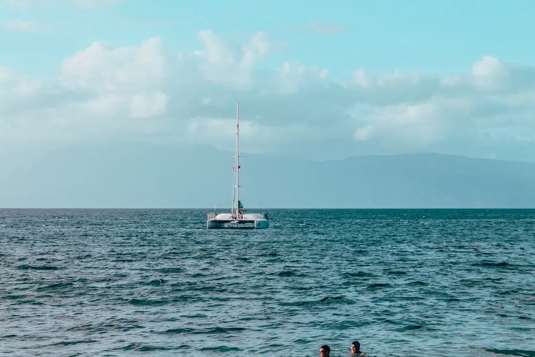 white sail boat on sea under white sky during daytime